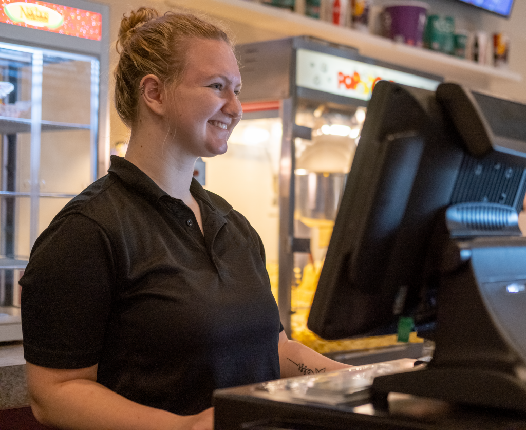 smiling cinema employee behind register at concessions counter