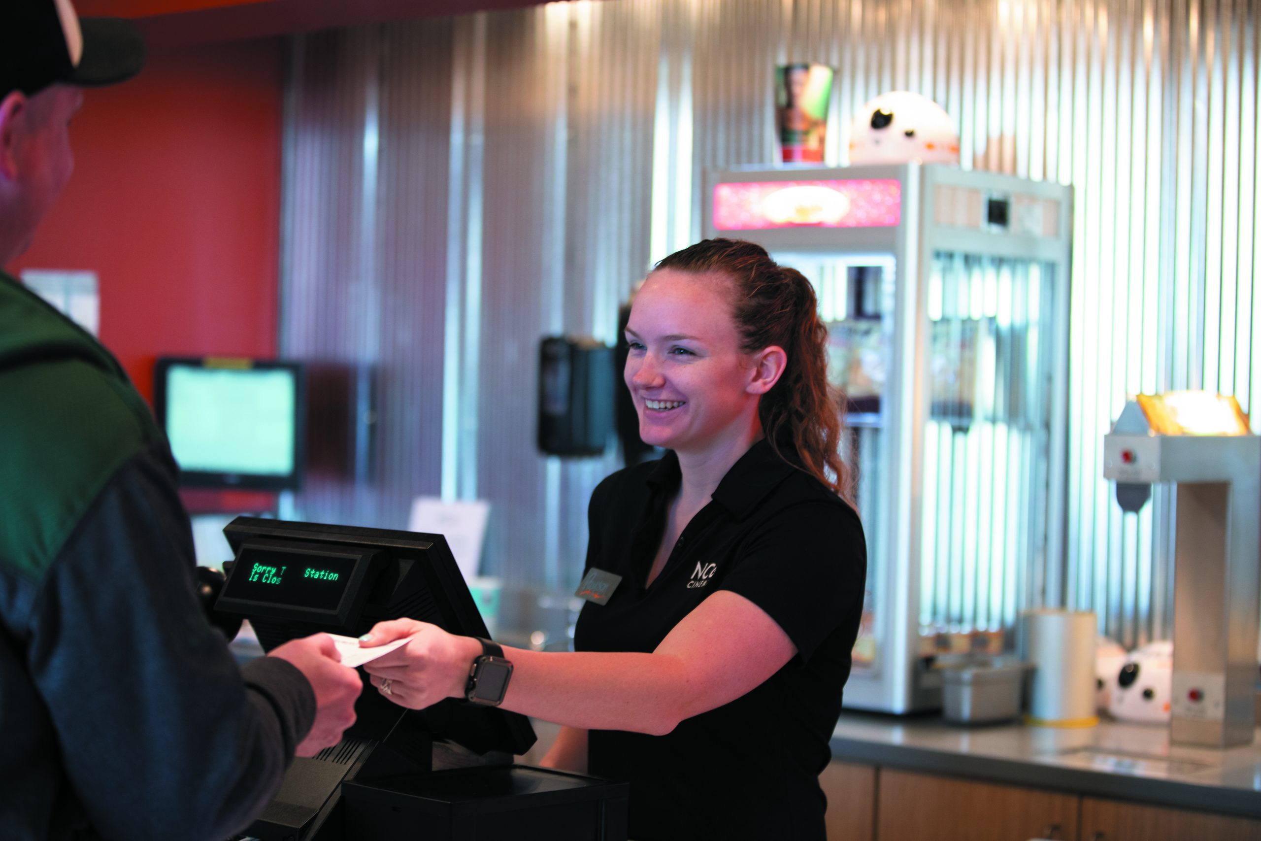 smiling woman behind register handing a receipt