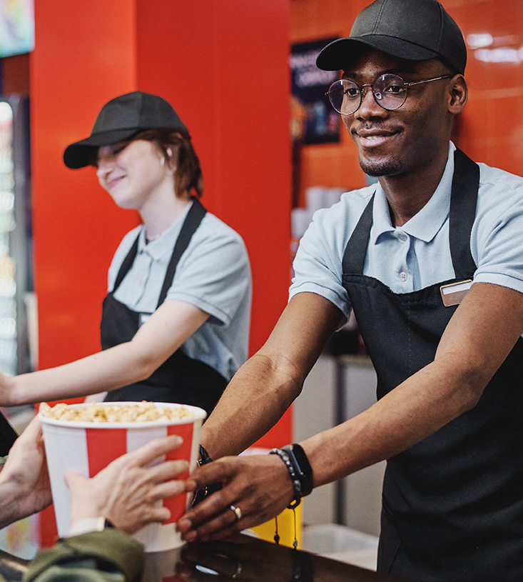 smiling employee handing popcorn bucket to customer